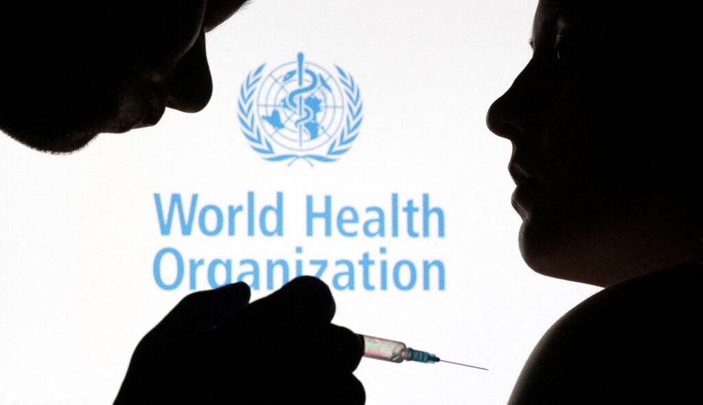 FILE PHOTO: People pose with syringe with needle in front of displayed World Health Organization (WHO) logo, in this illustration taken December 11, 2021. REUTERS/Dado Ruvic